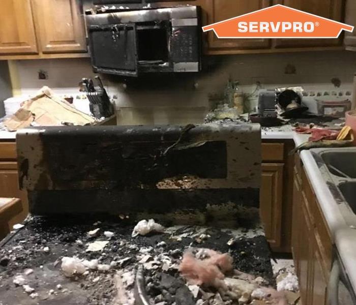 Fire damaged stove and microwave in a residential kitchen.